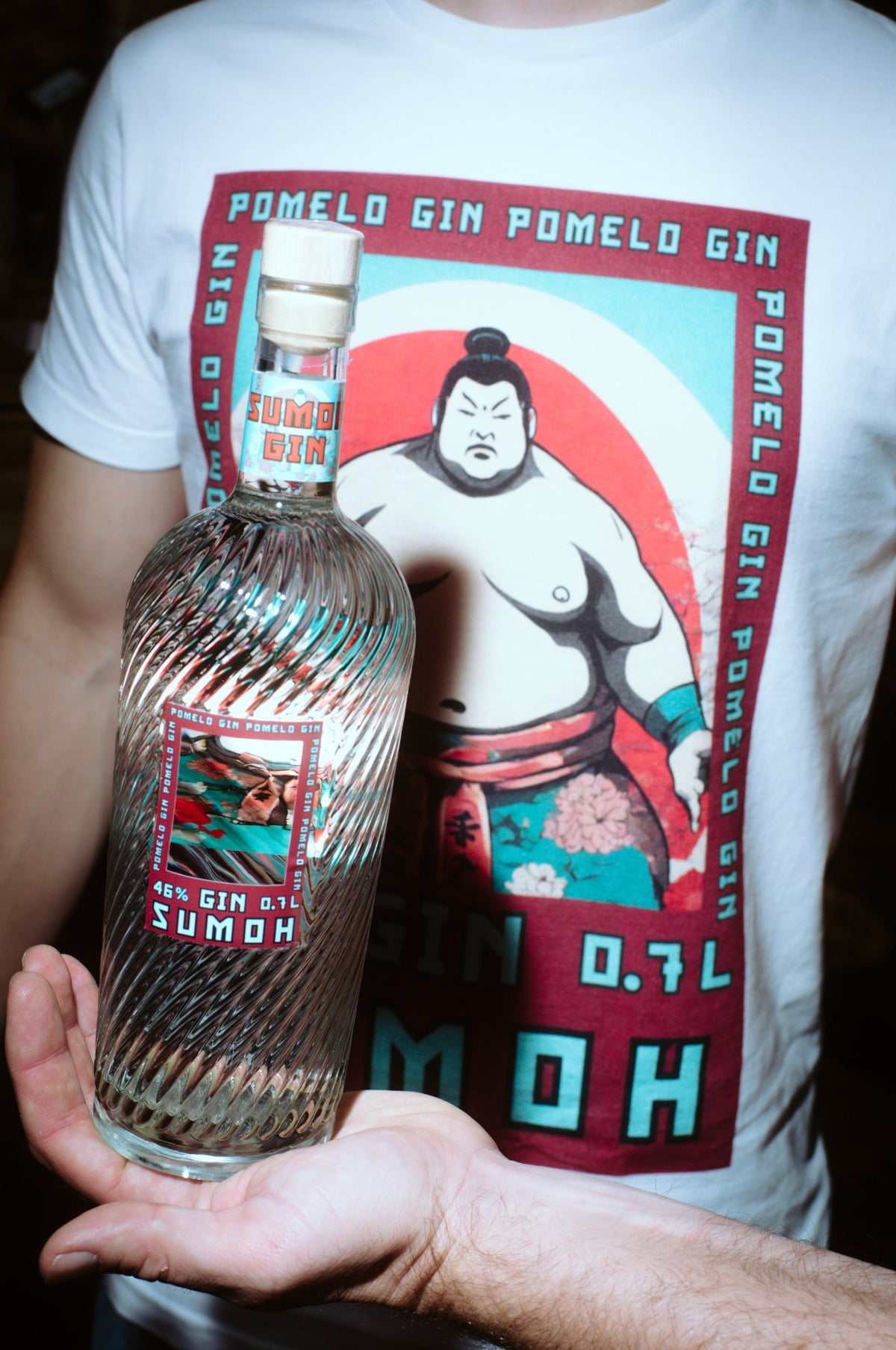 Sumoh Gin Flasche 0,7 l in der Hand vor Sumo-Motiv – Pomelo Gin, 46 % vol
