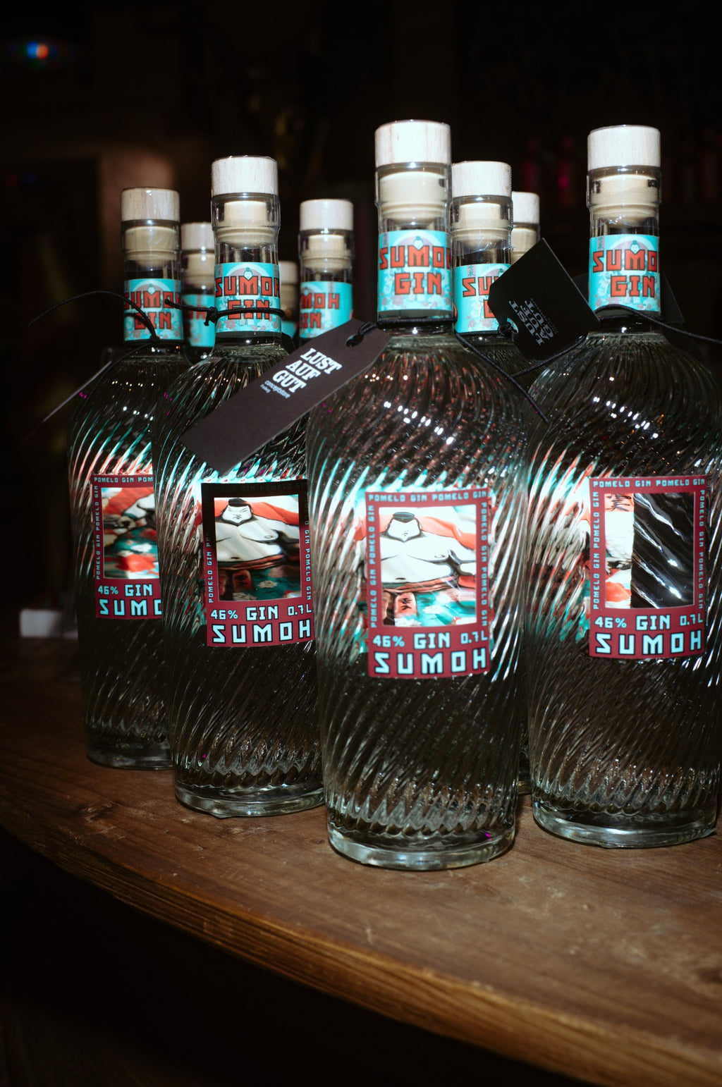 Mehrere Flaschen Sumoh Pomelo Gin auf einem Holztresen